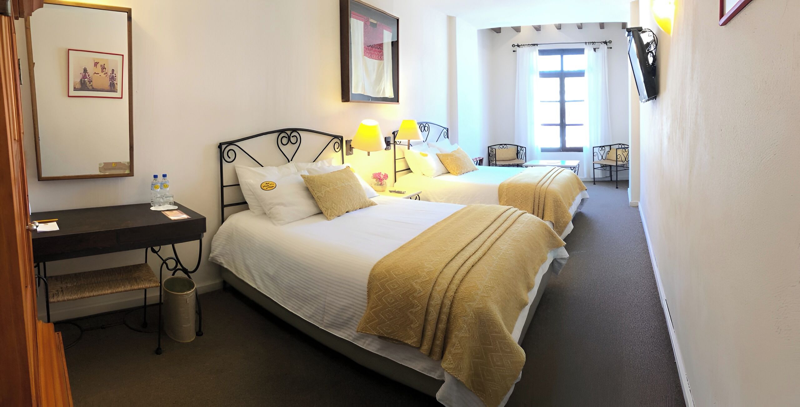 Una habitación de hotel con dos camas, un escritorio, una silla y una ventana.