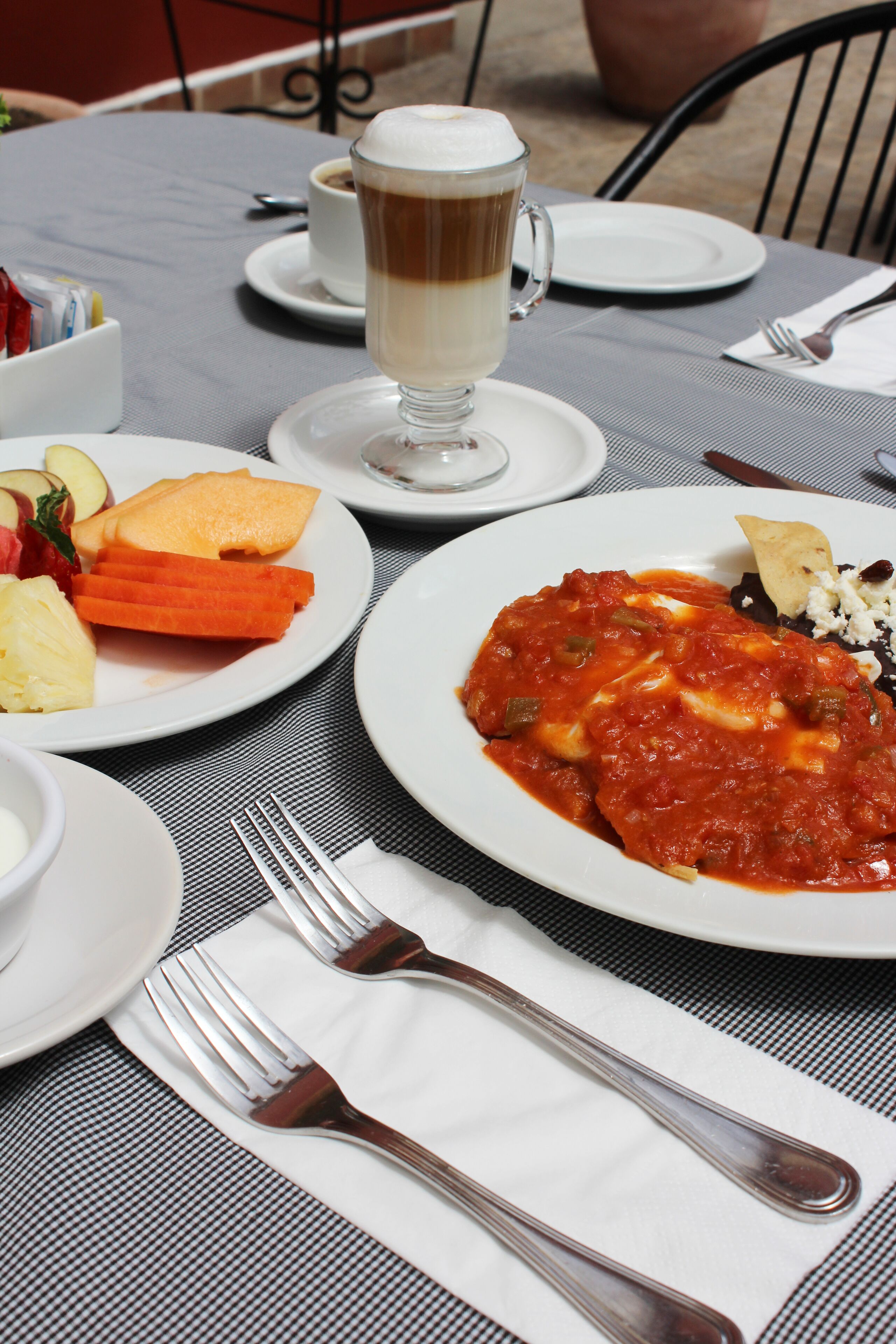 Een gedekte tafel met borden eten, een kop koffie en bestek.