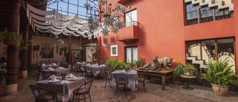Un espace de restauration intérieur avec des tables dressées pour les clients, entouré de plantes en pot et d’éléments décoratifs.
