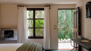 A bedroom with a bed, a TV mounted on the wall, a desk with a chair, and a window with curtains. - Posada Real de Chiapas (San Cristóbal de las Casas)
