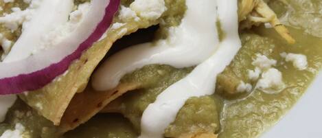 A plate of nachos topped with sour cream, crumbled cheese, and red onion slices.