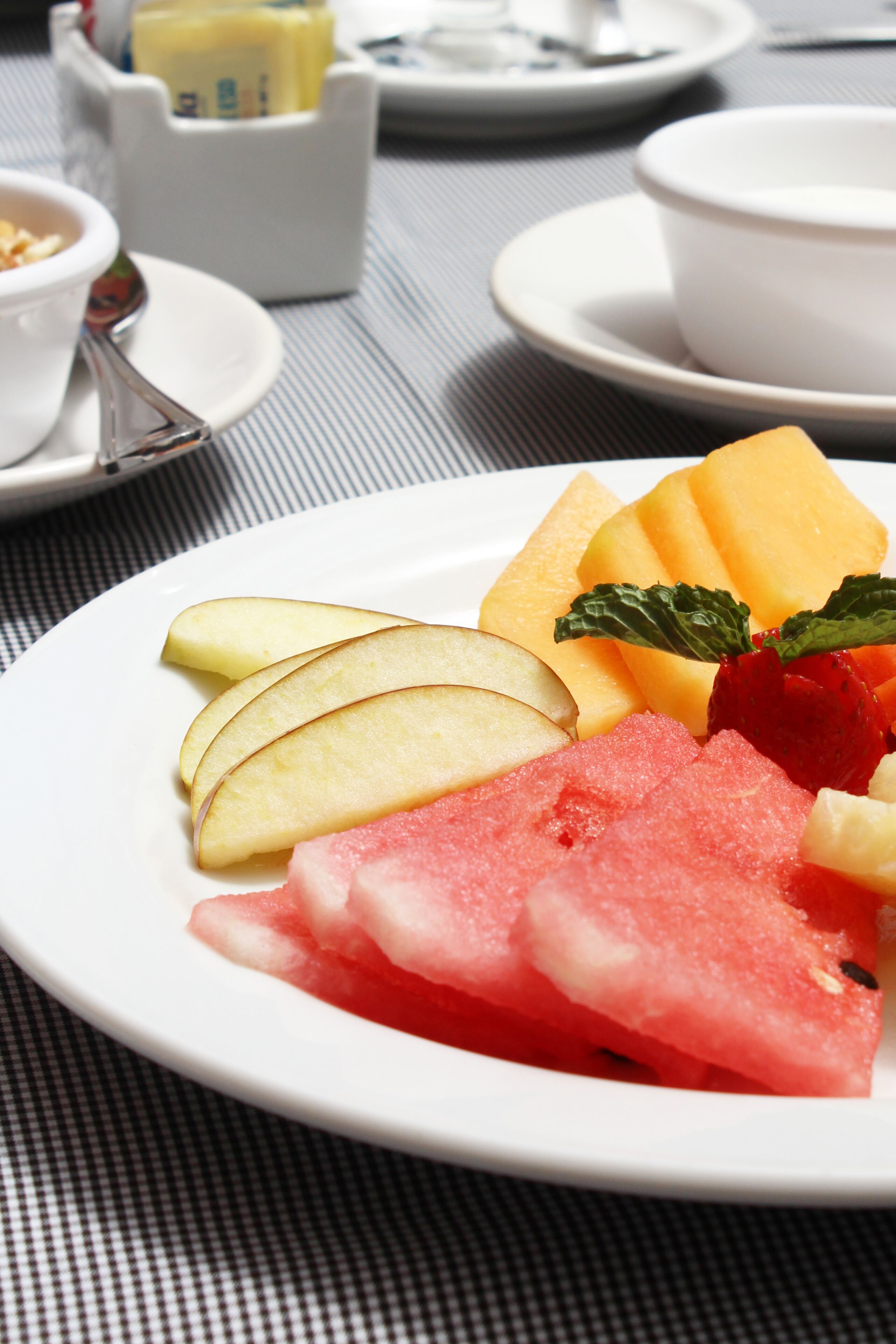 Un piatto di frutta con anguria, fragole e melone su un tavolo.