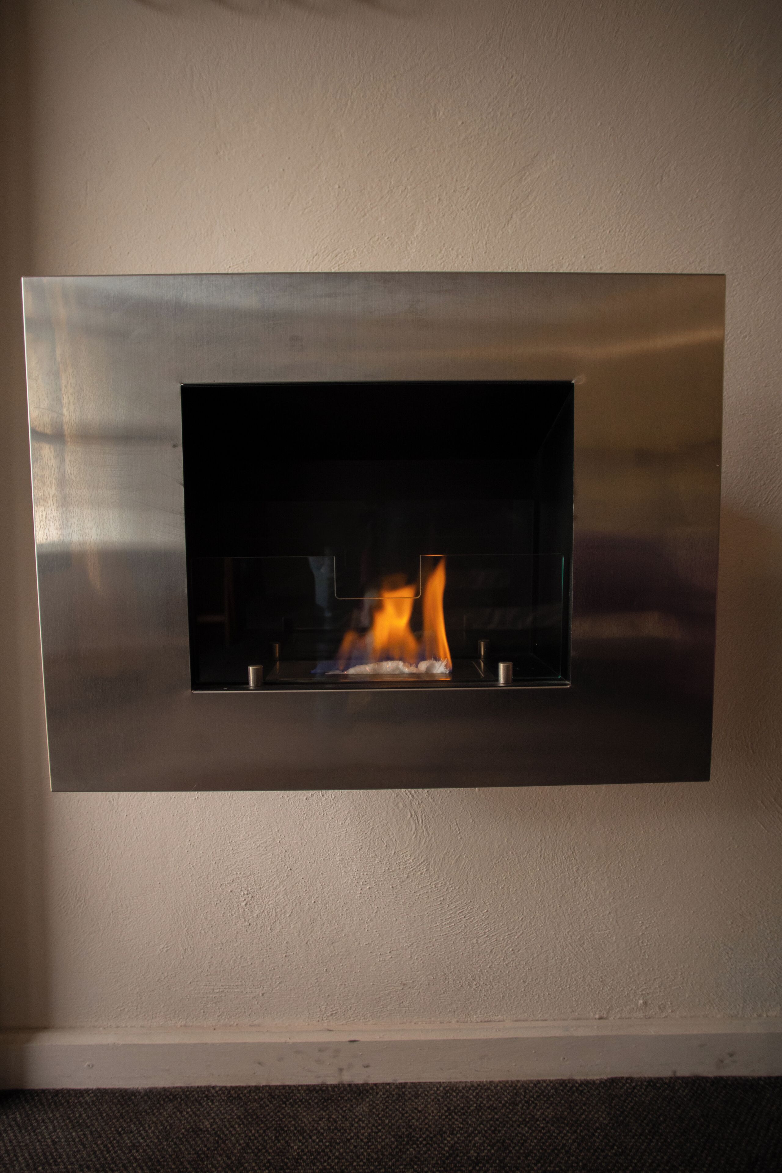 Ein moderner Kamin mit Metallrahmen und Glasfront, darin brennt ein Feuer.