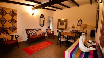 A cozy living room with a sofa, chairs, a dining table, and a colorful rug.