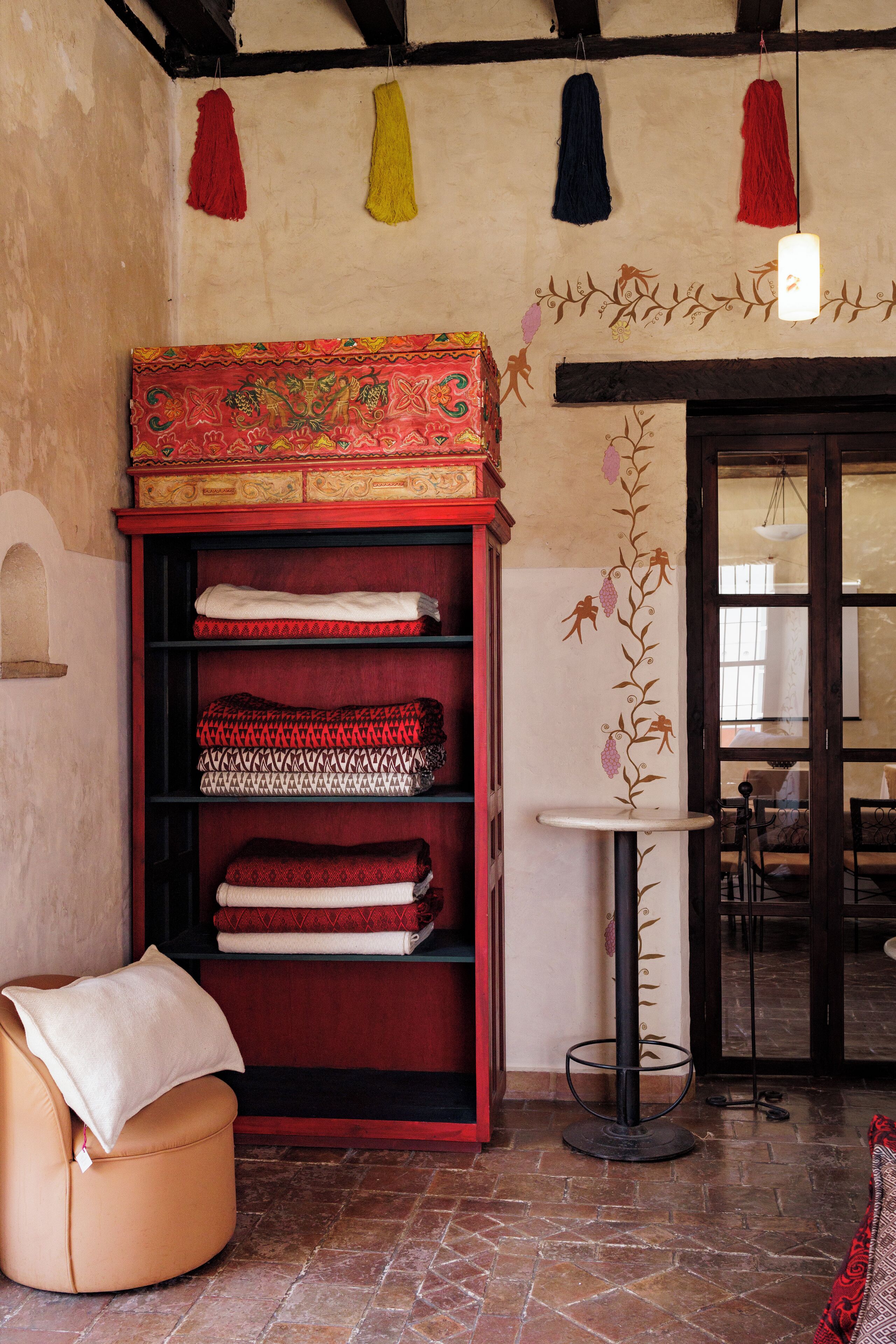 A room with a red bookshelf, a small round table, and a patterned wall.