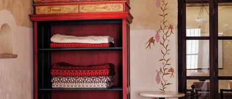 Una habitación con una estantería roja, una mesa redonda pequeña y un papel tapiz estampado.