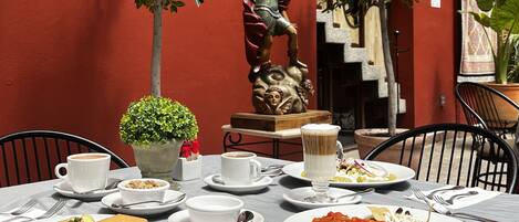 A restaurant with a red exterior, outdoor seating, and a variety of dishes on the table.