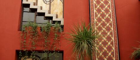 Un edificio rojo con una escalera, un tapete estampado y mobiliario de mimbre.