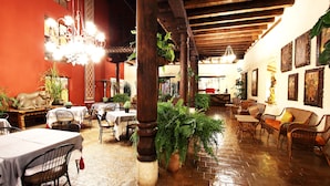 A restaurant with wooden beams, tables, chairs, and potted plants. - Posada Real de Chiapas (San Cristóbal de las Casas)