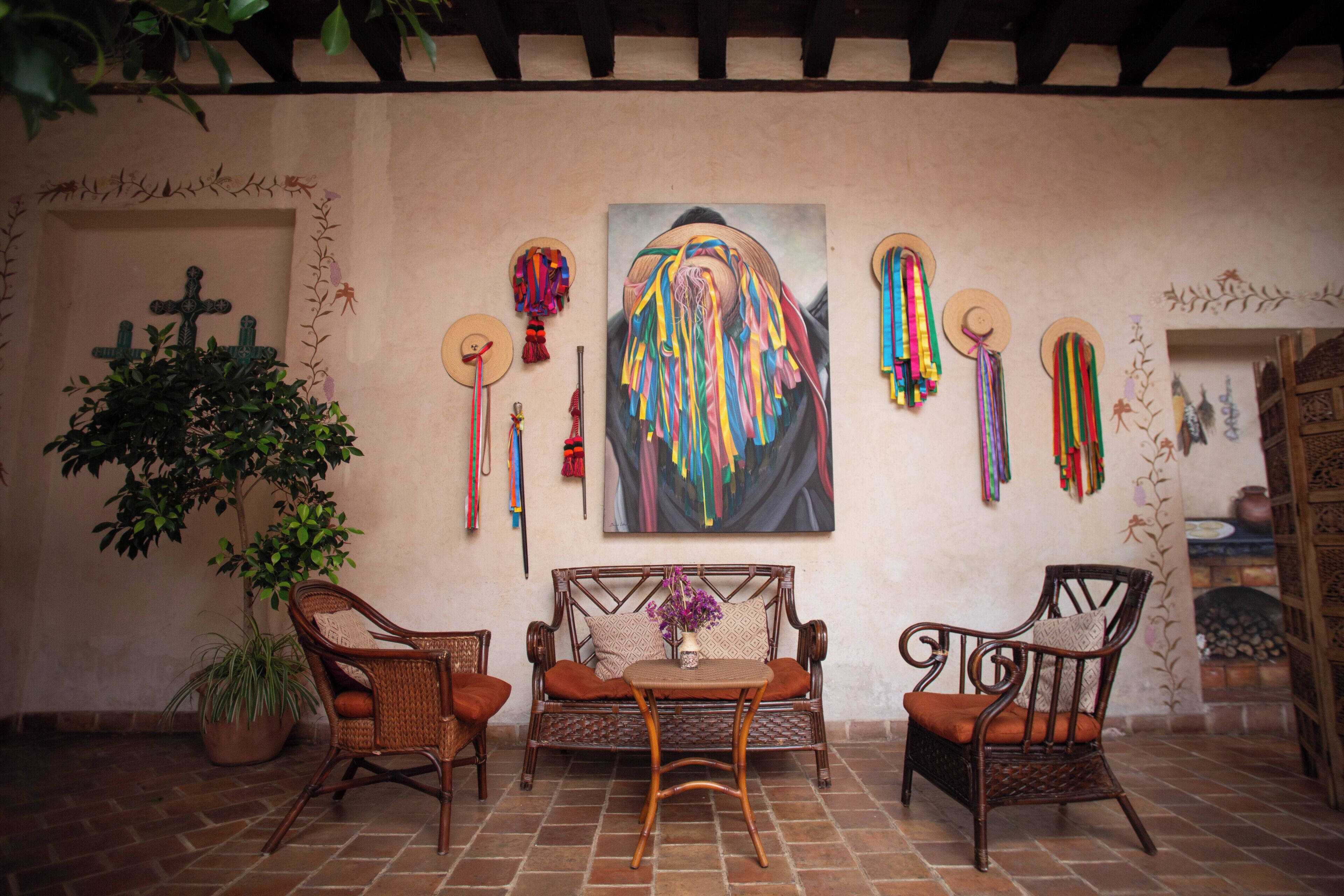 A patio area with wicker furniture, a table, and a large painting on the wall.