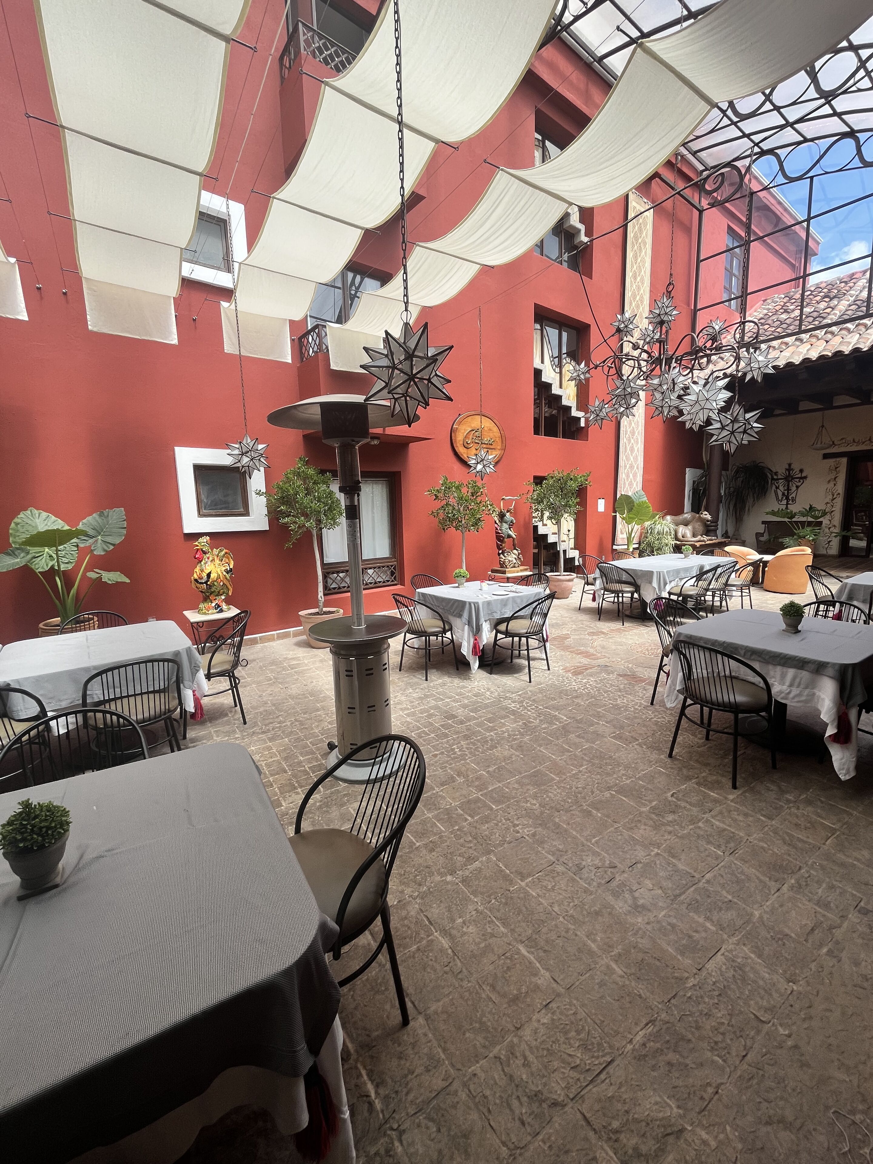 An outdoor patio with tables and chairs, decorative star-shaped hanging lights, and potted plants.