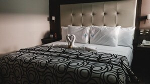 A neatly made bed with a patterned bedspread, a heart-shaped towel, and a tufted headboard. - Hotel Flamingo (Merida)
