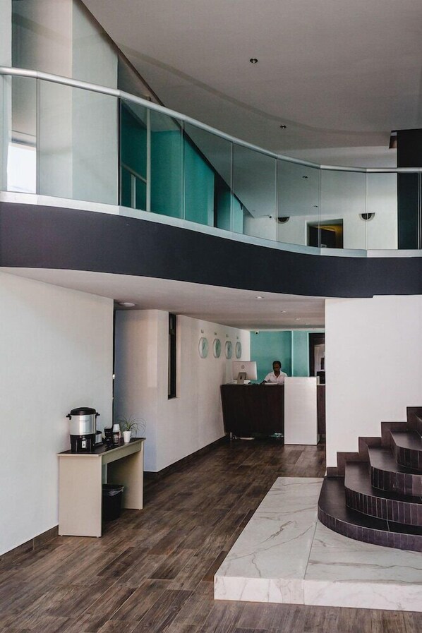 A modern hotel lobby with a staircase, a reception desk, and a coffee station. - Hotel Flamingo (Merida)