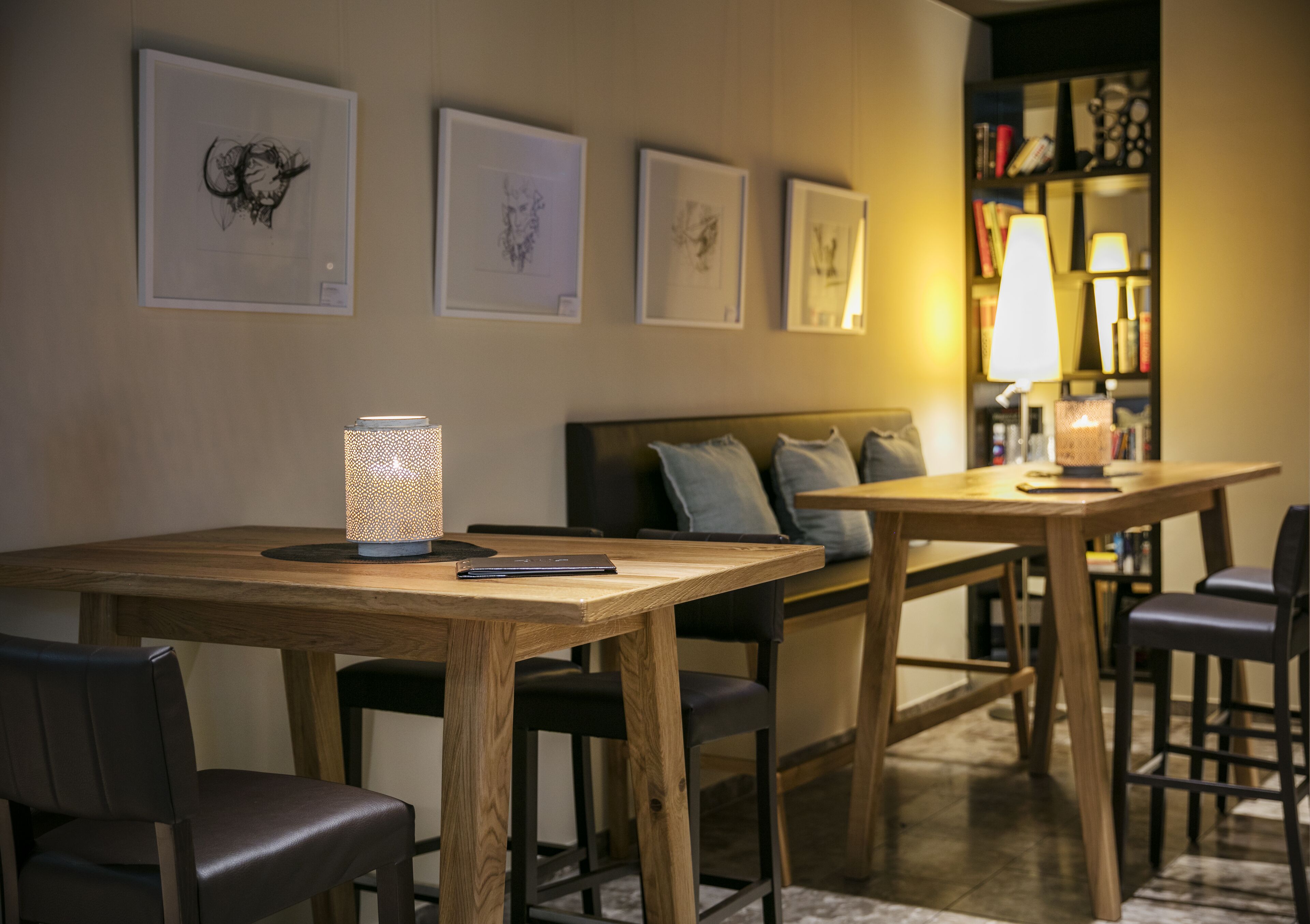 A cozy room with a wooden dining table, chairs, a sofa, and a bookshelf with books and decorative items.