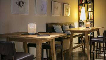 A cozy room with a wooden dining table, chairs, a sofa, and a bookshelf with books and decorative items.