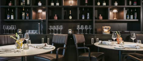 Un restaurante con paneles de madera oscura, varias mesas con sillas y una pared llena de botellas de vino.