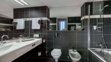 Un baño moderno con lavamanos grande, inodoro, bidé y zona de ducha con mampara de vidrio.