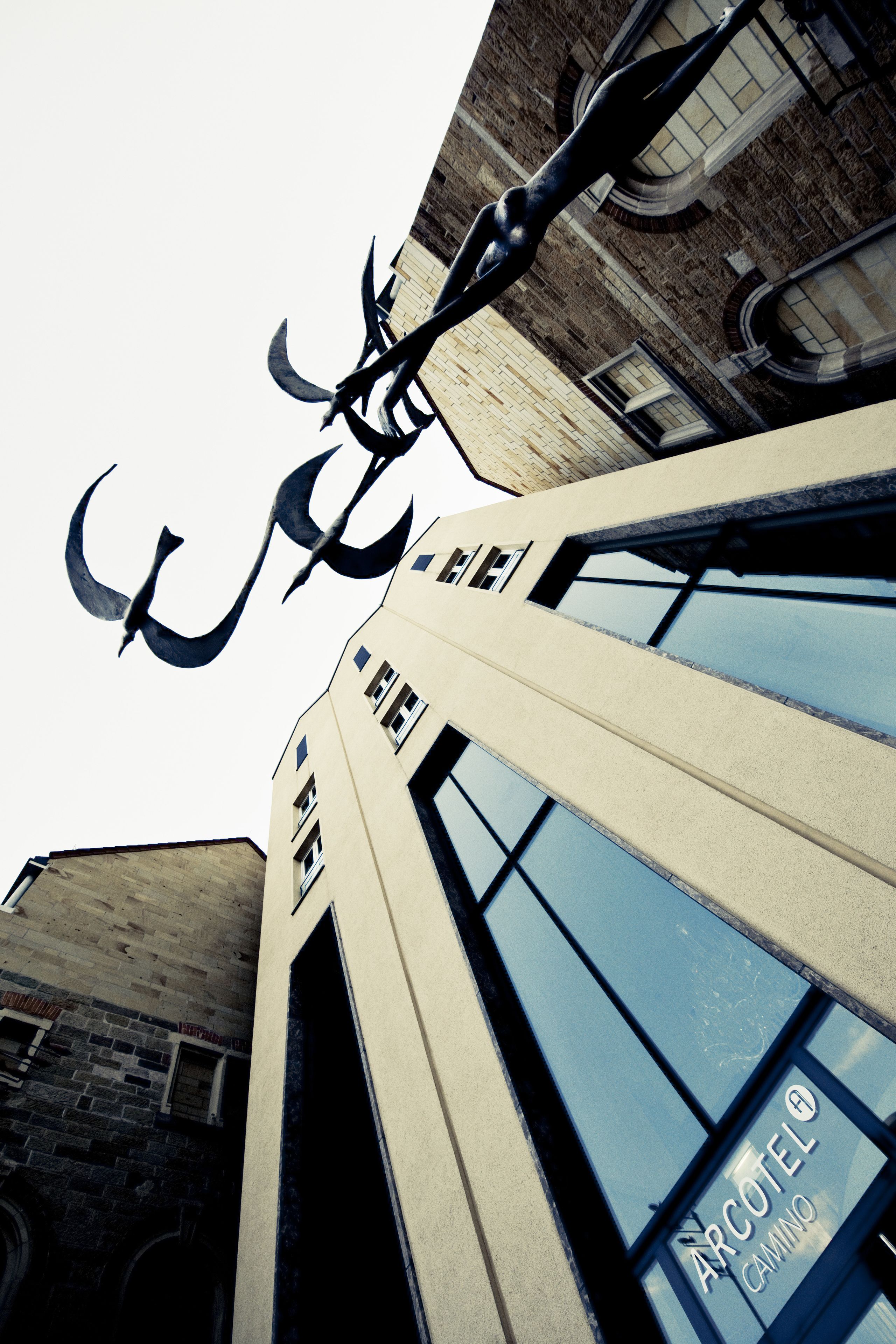 A building with a sign reading "ARCOTEL Camino" and a large metal sculpture above the entrance.