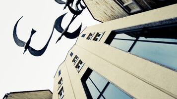 A building with a sign reading "ARCOTEL Camino" and a large metal sculpture above the entrance.