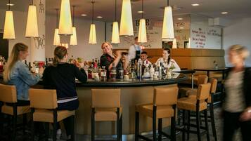 Een bar met meerdere krukken en hangende hanglampen.