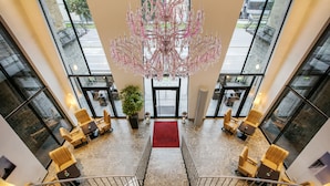 Un hall d’entrée spacieux, agrémenté d’un magnifique lustre, de sièges confortables et d’un tapis rouge menant à l’entrée.