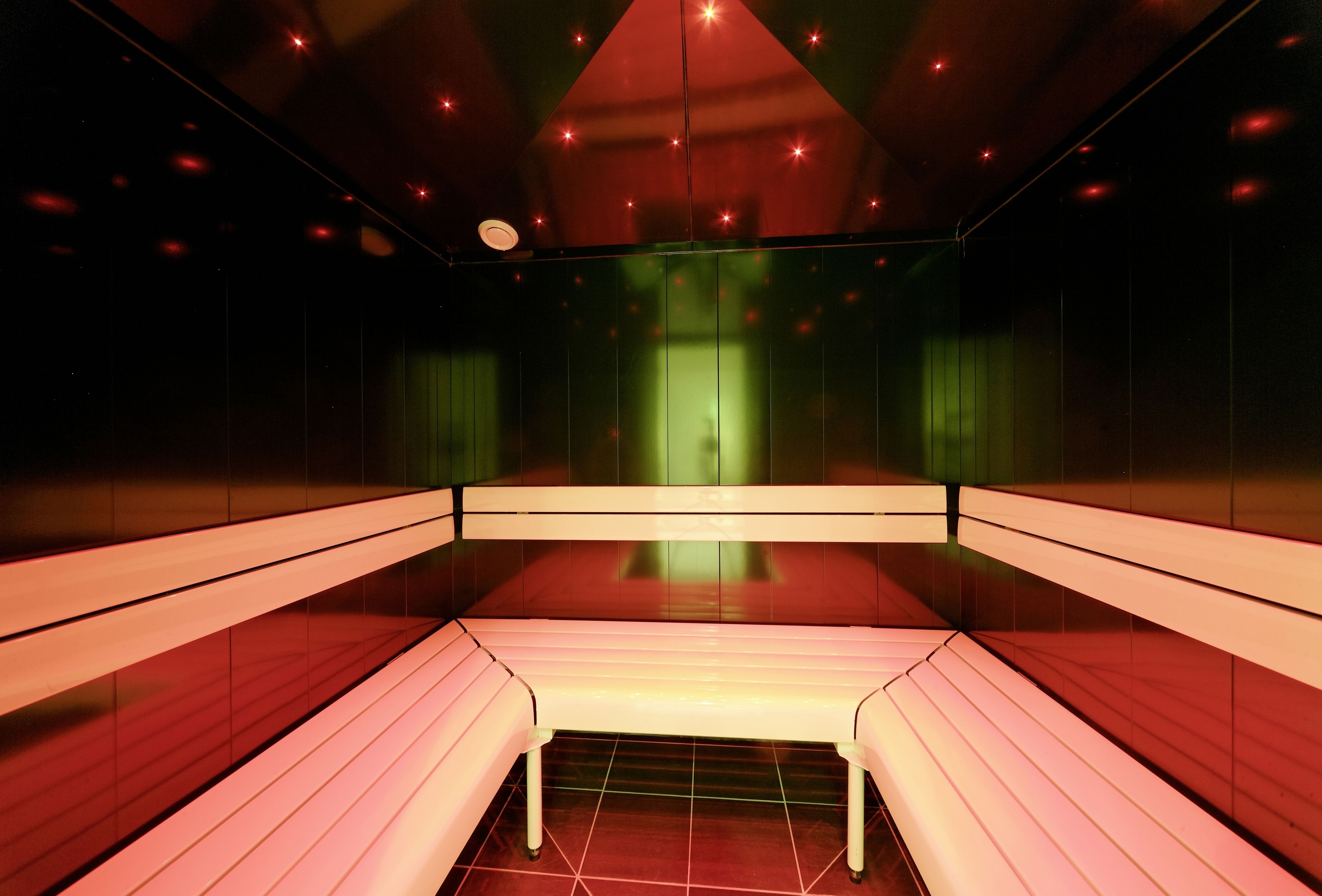 Una habitación con un banco largo, una pantalla verde y un suelo rojo.