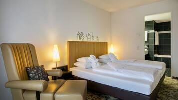 Een hotelkamer met een groot bed, een stoel, twee bedlampen en een decoratie aan de muur.