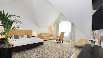 Ein modernes Hotelzimmer mit einem großen Bett, einer Couch, einem Sessel und einem Fernseher.