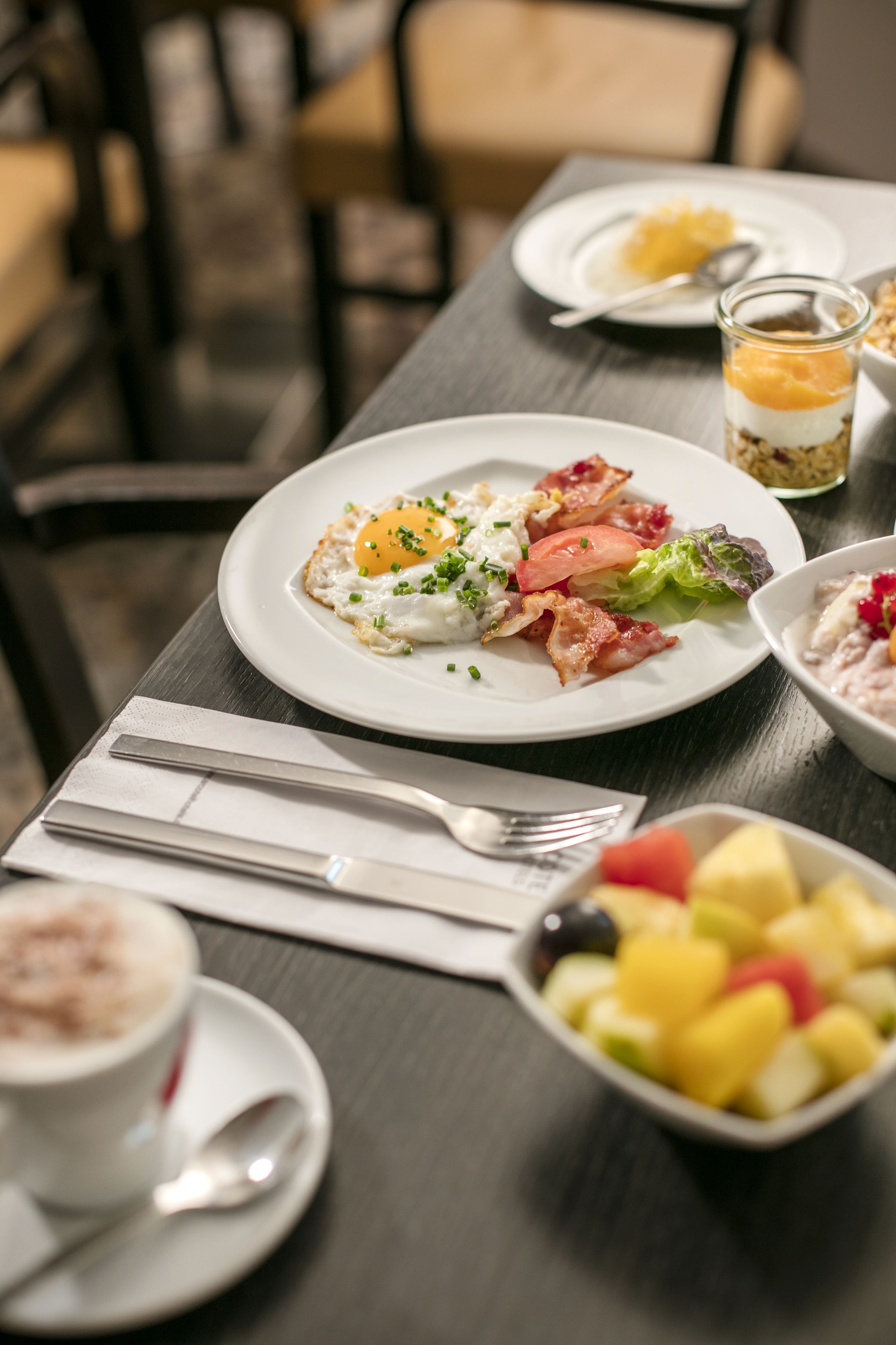Ein Esstisch mit Speisen, Obstschale und einer Kaffeetasse.