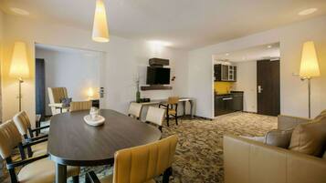 Habitación de hotel con comedor, sofá, televisión y cocina.