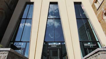 Un edificio moderno con grandes ventanales, una escalera que conduce a la entrada y letreros para un bar y un Archotel.