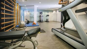 Un gimnasio con cinta de correr, pelotas de ejercicio y un estante fijado a la pared.