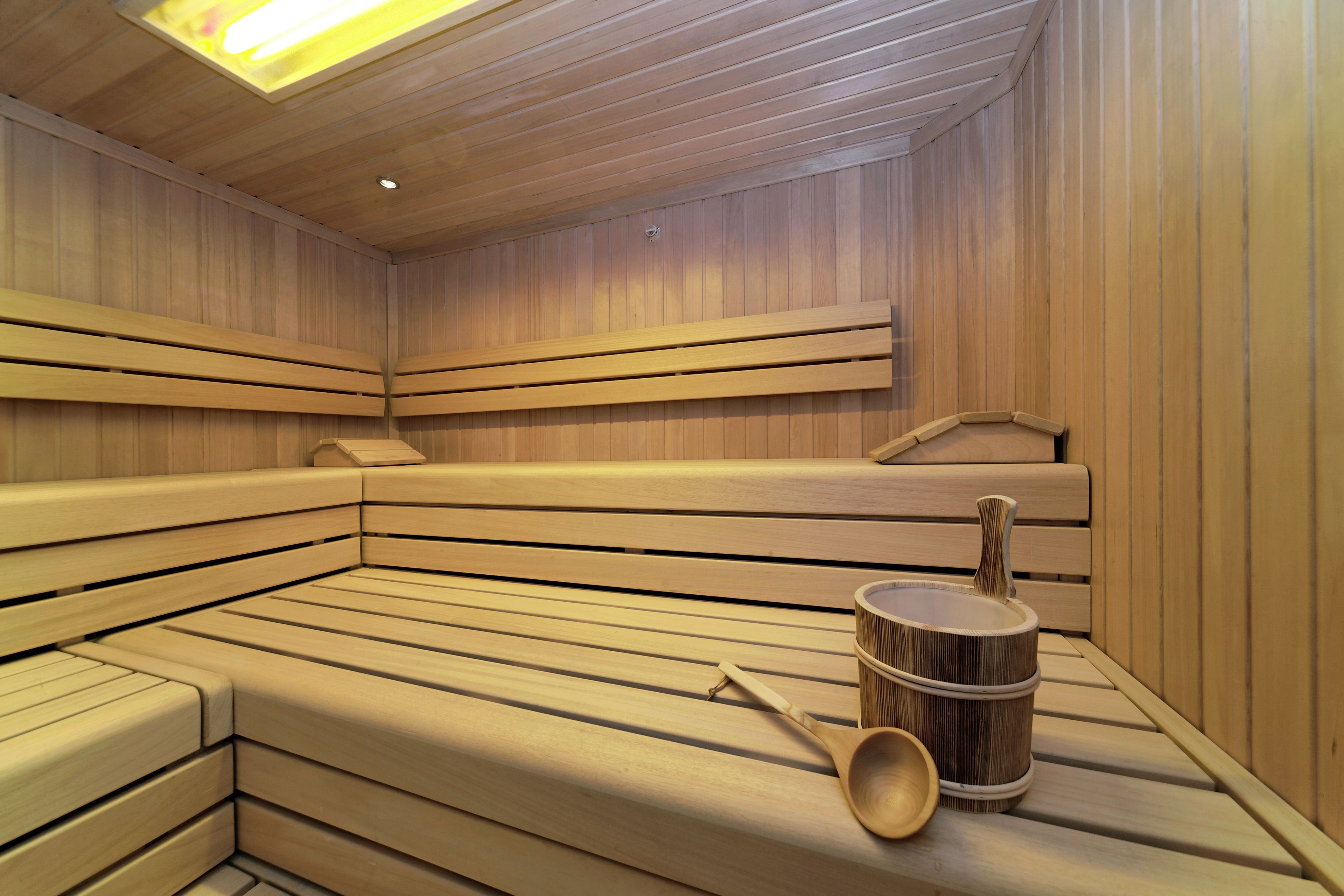 Un sauna avec des bancs en bois et un seau en bois accompagné d’une louche.