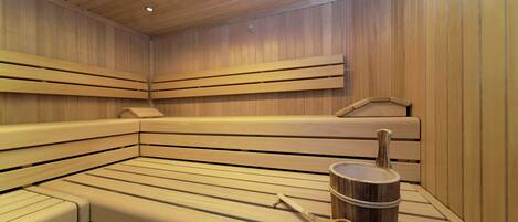 A sauna with wooden benches and a wooden bucket with a ladle.