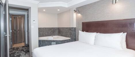 A hotel room with a large bed, a built-in bathtub, and a separate shower area.