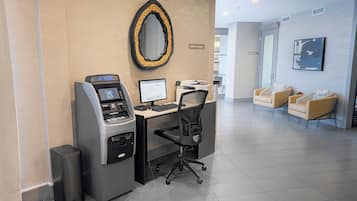Centro de negocios con cajero automático, computadora y silla de oficina.