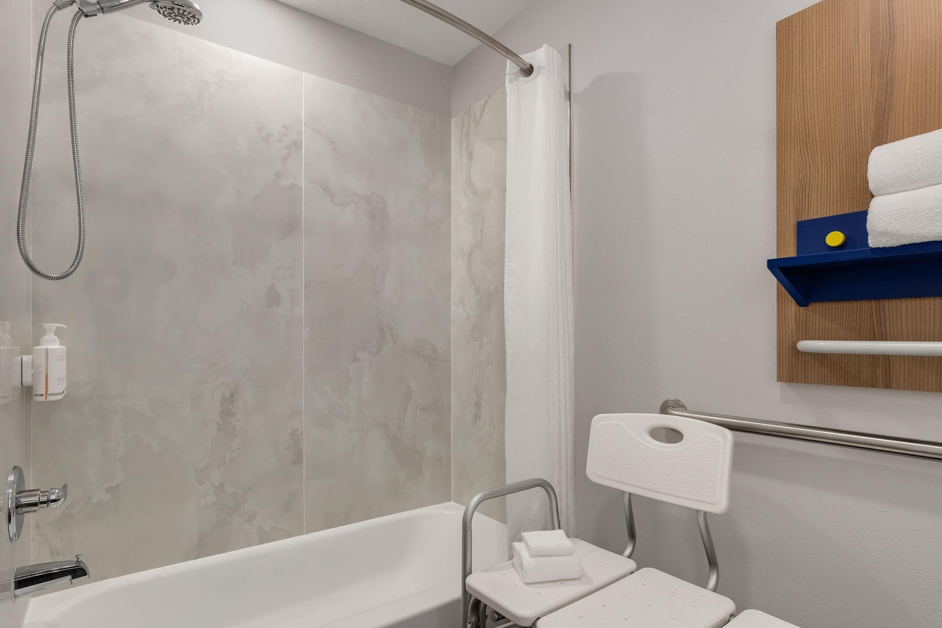 Ein Badezimmer mit Badewanne, Dusche und Handläufer.