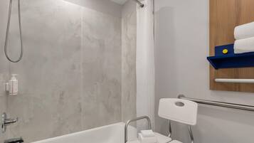 Ein Badezimmer mit Badewanne, Dusche und Handläufer.
