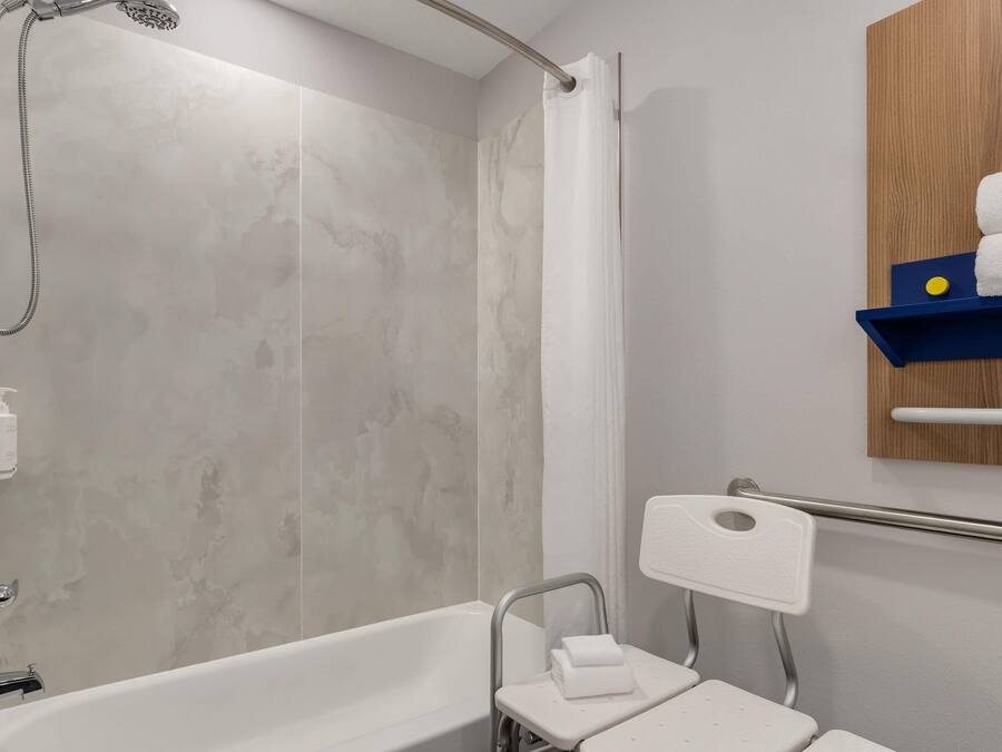 Ein Badezimmer mit Badewanne, Dusche und Handläufer.