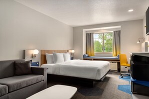 A hotel room with a bed, a desk, a chair, a sofa, and a TV. - Microtel Inn & Suites by Wyndham Culpeper (Culpeper)