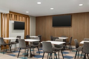 A conference room with white tables and grey chairs, a flat-screen TV mounted on the wall, and wooden paneling on the walls. - Microtel Inn & Suites by Wyndham Culpeper (Culpeper)