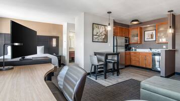 Una habitación de hotel moderna con una cama grande, un escritorio, un comedor y una kitchenette.