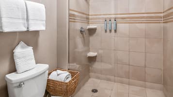 A bathroom with a toilet, a shower stall, and a wicker basket with towels.