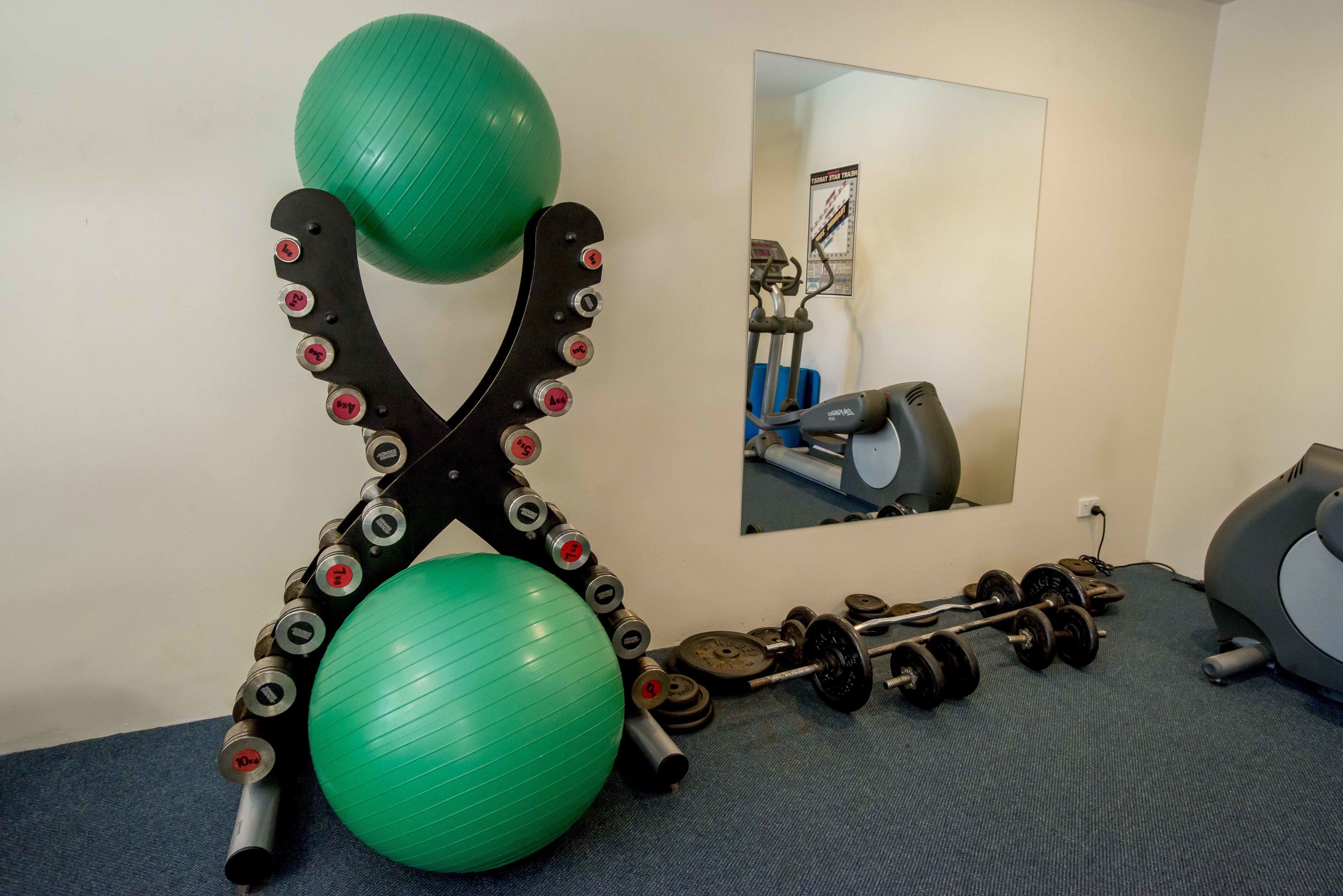 Un gimnasio con pelotas de ejercicio, mancuernas y un espejo.