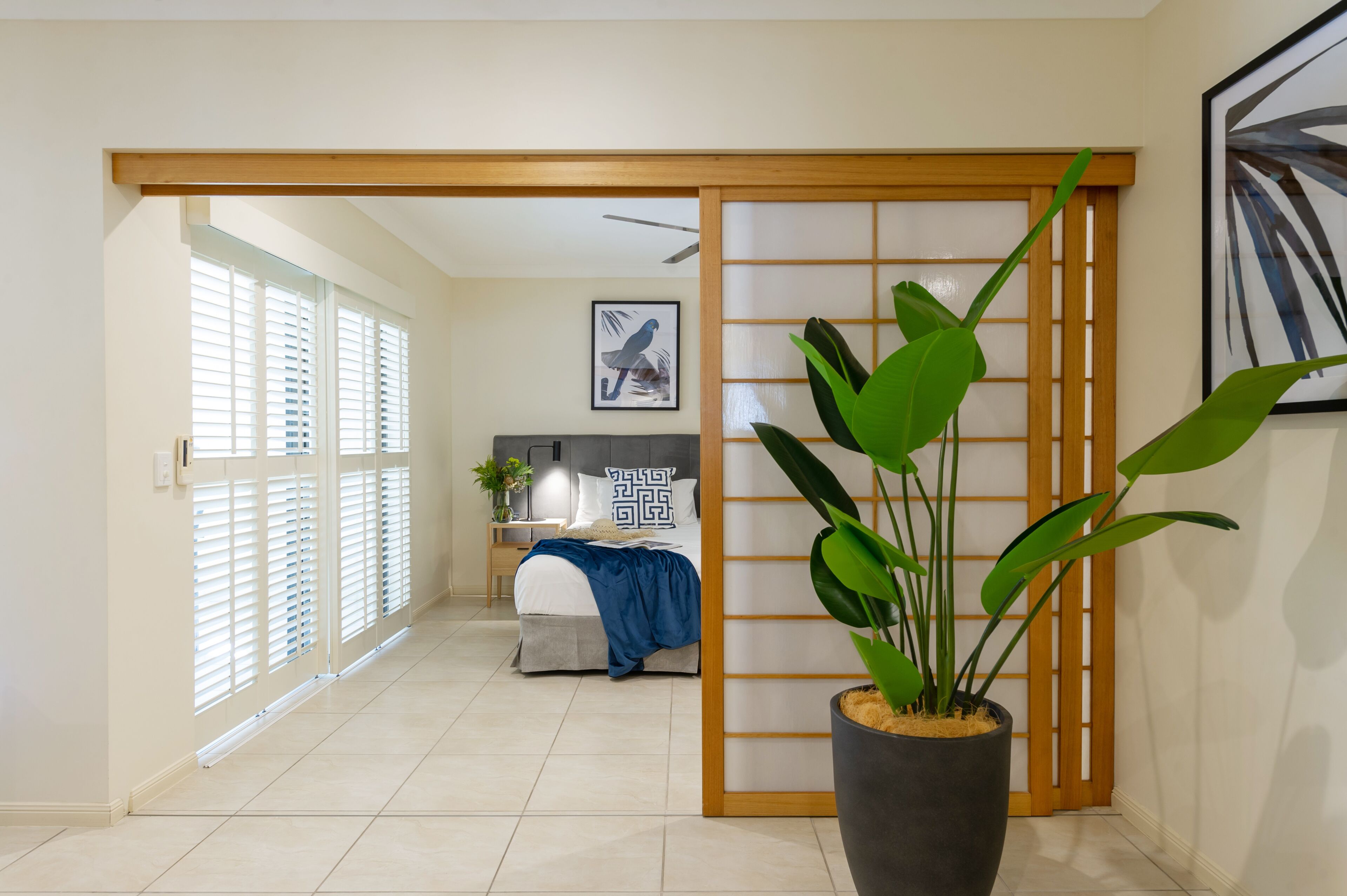 A modern bedroom with a bed, bedside table, and a large potted plant.