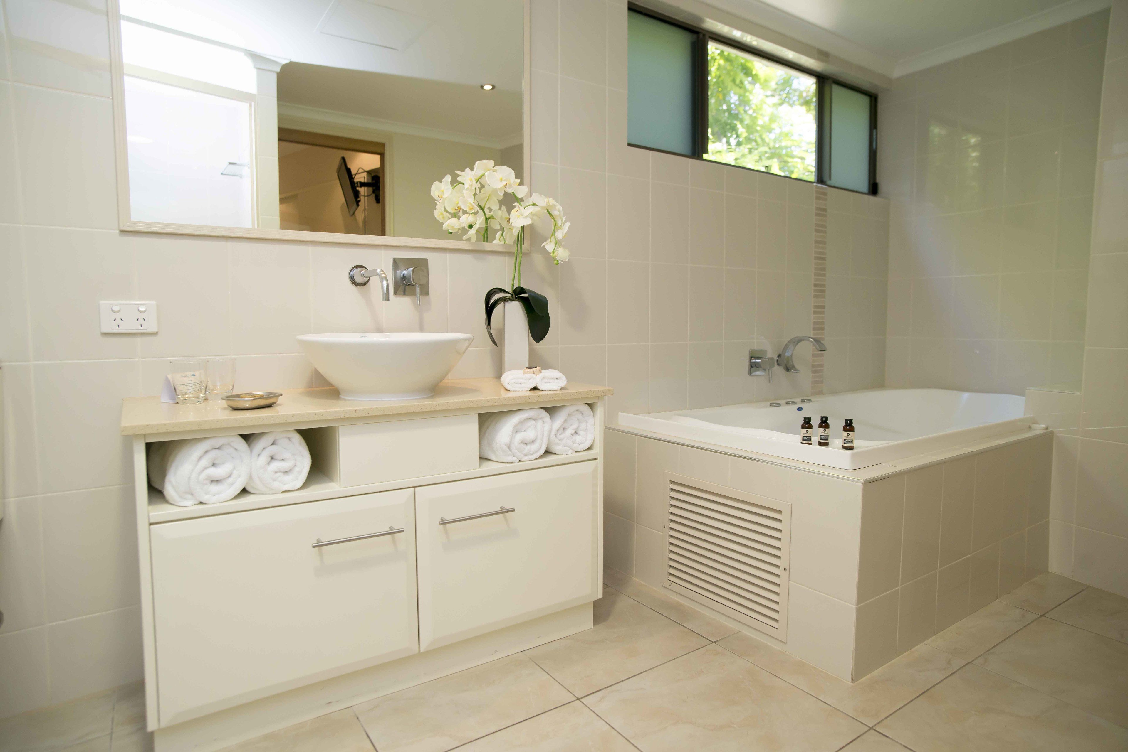 A modern bathroom with a large bathtub, a sink, and a vanity with towels.