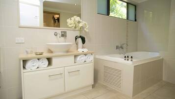 A modern bathroom with a large bathtub, a sink, and a vanity with towels.