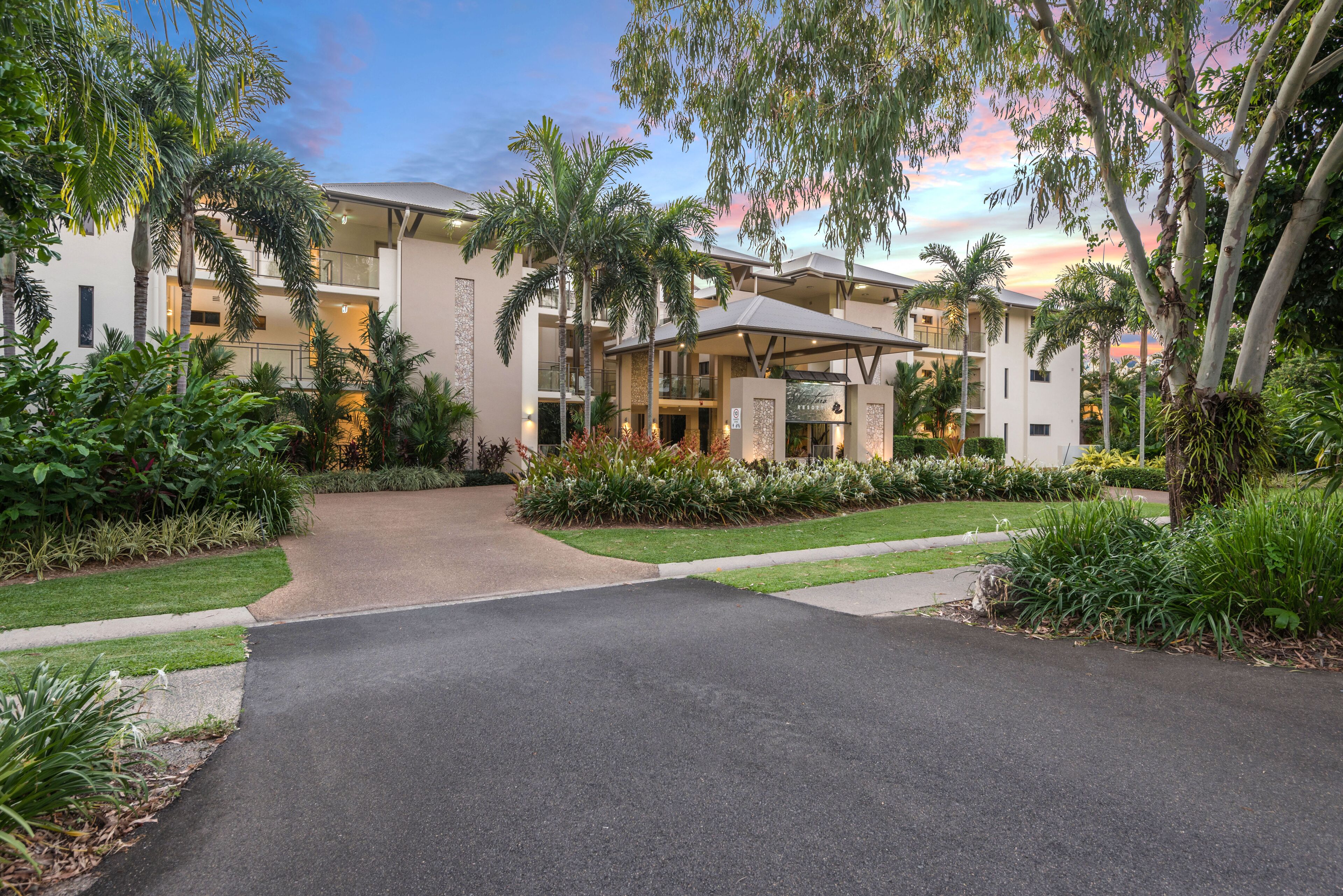 A modern hotel with a central courtyard, surrounded by lush greenery and palm trees.