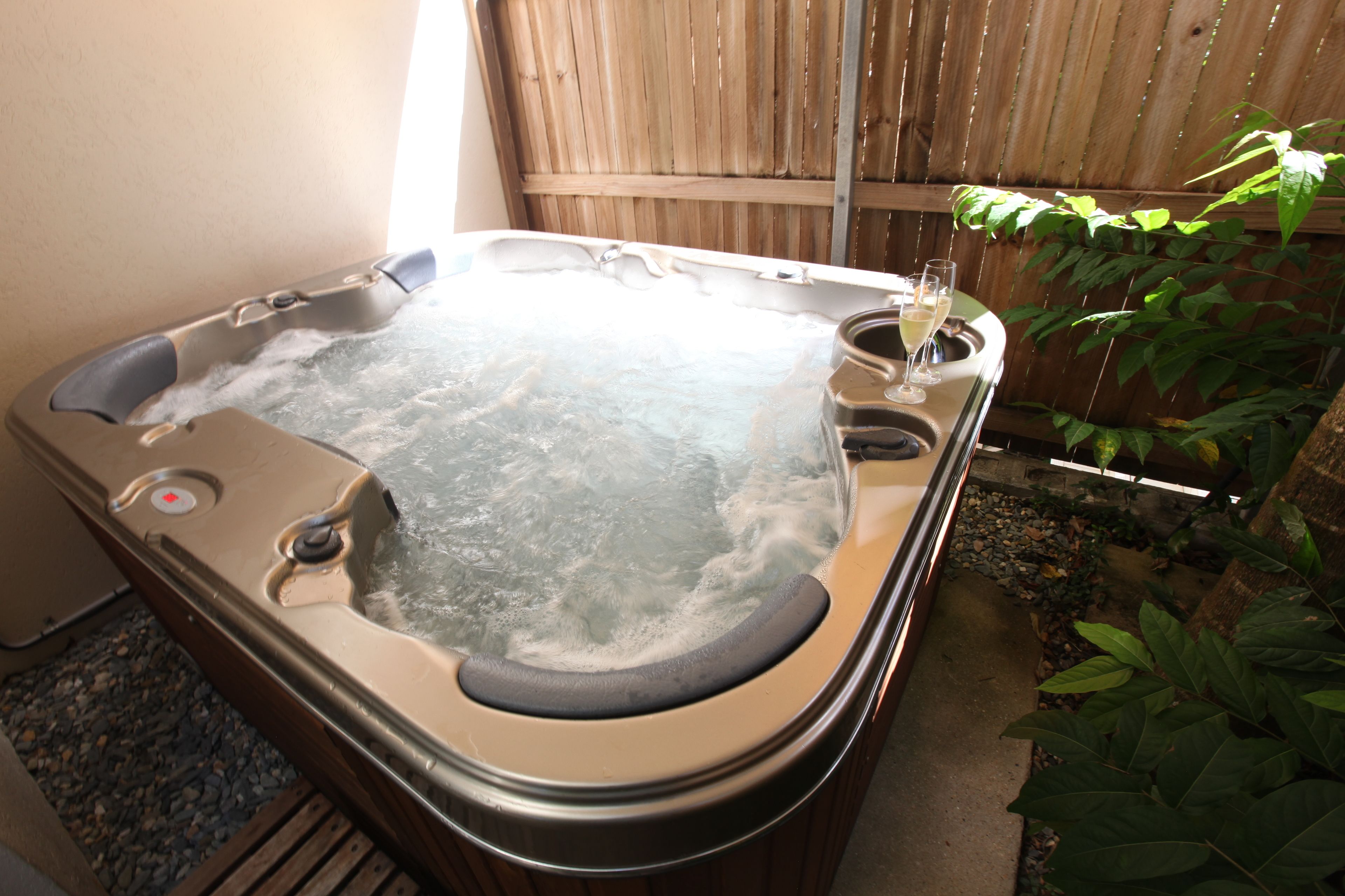 Un jacuzzi con terraza de madera y una copa de champán.