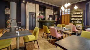 A restaurant with wooden flooring, a bar area, and a variety of colorful chairs and tables. - Boutique Hotel KRISTOFS (Riga)